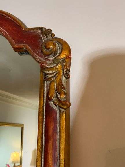 Ornate Mirror With Red and Gold Trim Featuring Scrolled Details