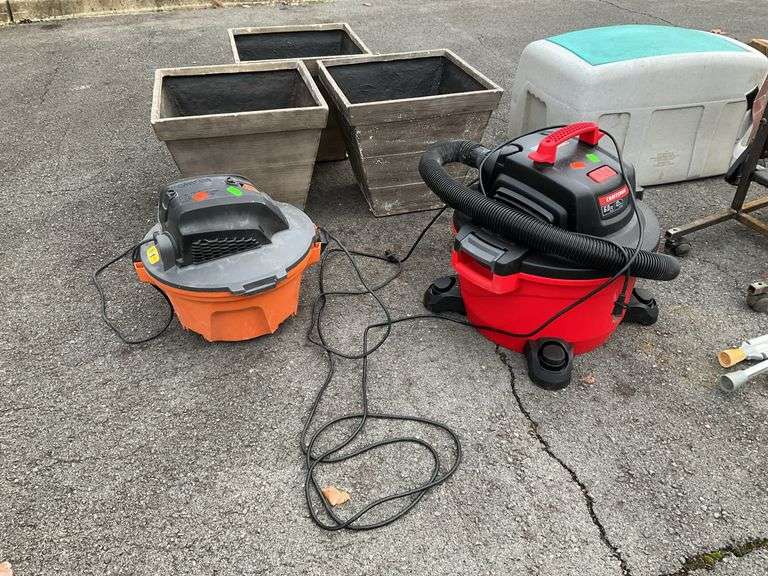 Two shop vacs, one missing the wheels,