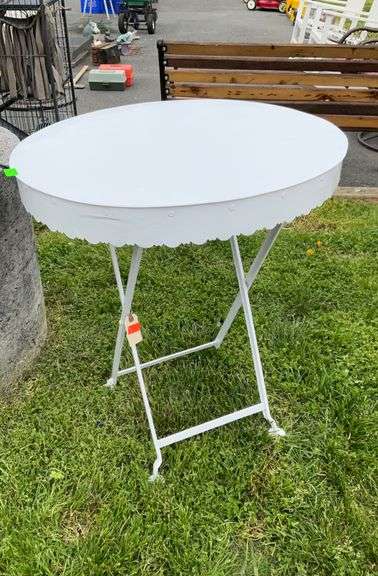 White painted metal oval top stand, folds, measures 25 inches oval by 29 inches tall