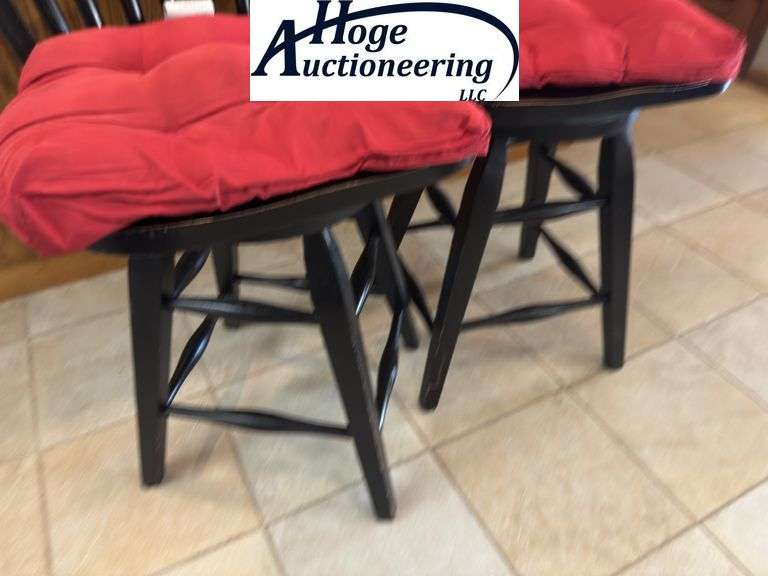 Black swivel wooden bar stool chairs with red cushions.
