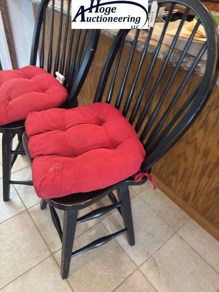Black swivel wooden bar stool chairs with red cushions.