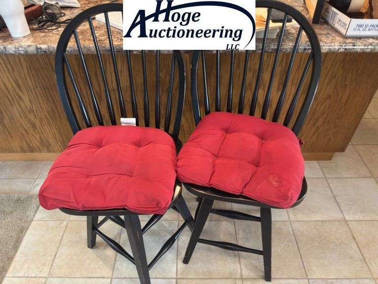 Black swivel wooden bar stool chairs with red cushions.