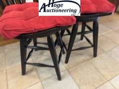 Black swivel wooden bar stool chairs with red cushions.
