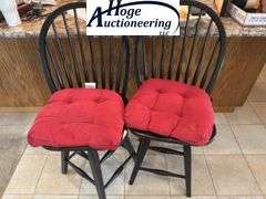 Black swivel wooden bar stool chairs with red cushions.