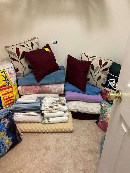 Contents of closet floor: sheets, blankets, throw pillows, luggage