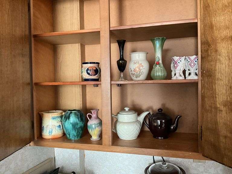 Contents of cupboard: pottery teapots and vases, blown glass bud vase