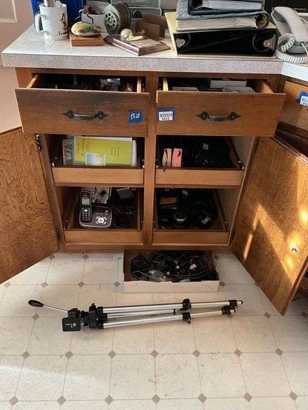 Contents of cupboard and two drawers: cameras w/ accessories, cordless phones, flashlights, tools, greeting cards, office supplies