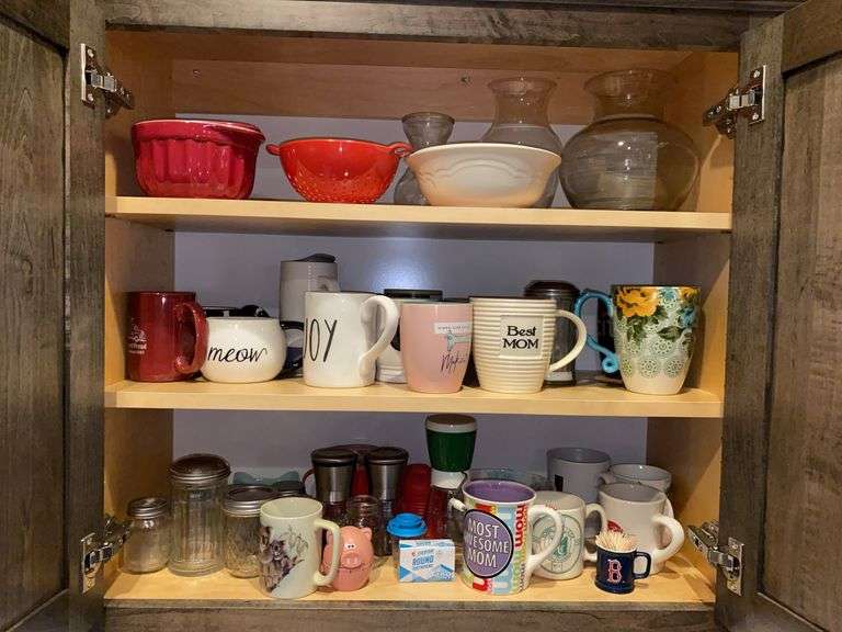 Contents of cupboard: mugs, pig timer, bowls, vases, colander