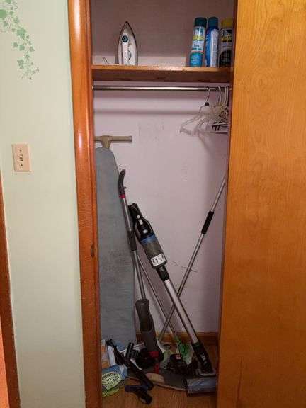 Contents of closet: stick vacuums, dust mop, ironing board, iron, spray starch