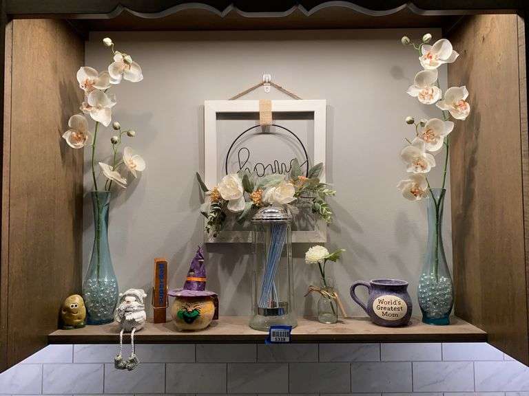 Contents of shelf: bud vases, faux orchids, straw jar, home plaque, decor items