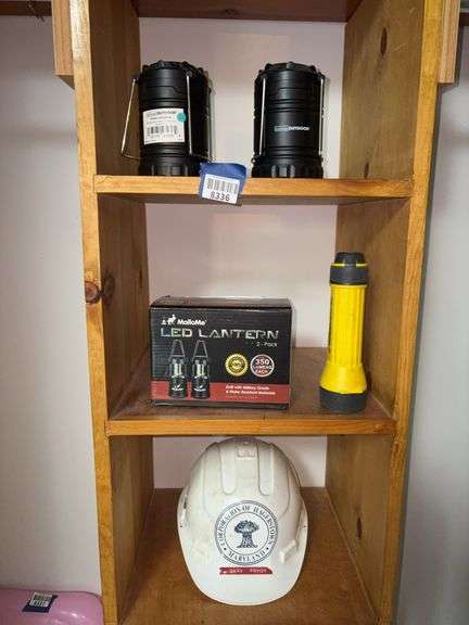Contents of three shelves: battery lanterns, flashlight, Hagerstown hardhat