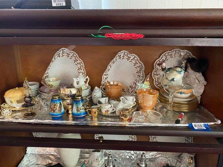 Contents of shelf: mini teaset, Fire King peach luster sugar/creamer, blown glass perfume bottle, butter pats, salt dips, small doll, misc