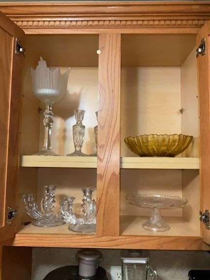Contents of cupboard: elegant glass 3-lite candleholders, cakestand, amber bowl, glass candlesticks, pedestal vase