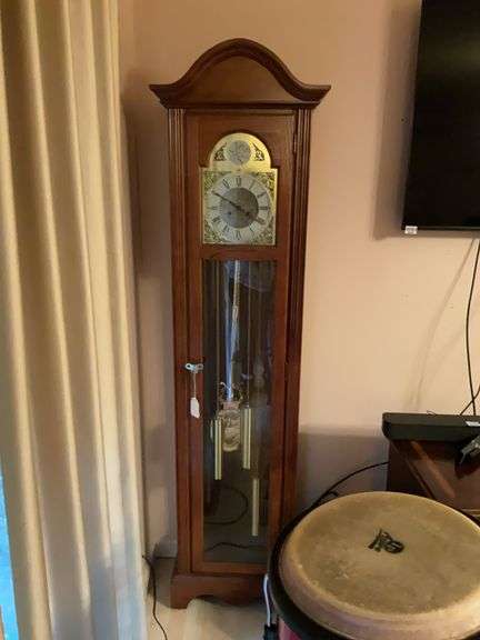 Oak finish tall case clock w/ metal face, glazed body door and sides, brass tone pendulum and weights 17 x 10 x 77