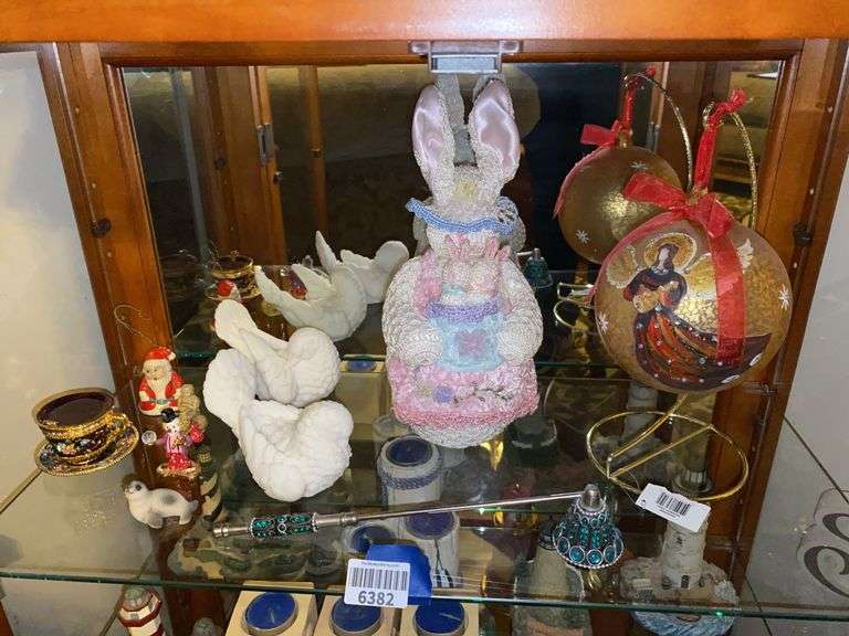 Contents of shelf: angel Christmas ornament, crocheted Easter rabbit, dove figurines, candle snuffer, misc