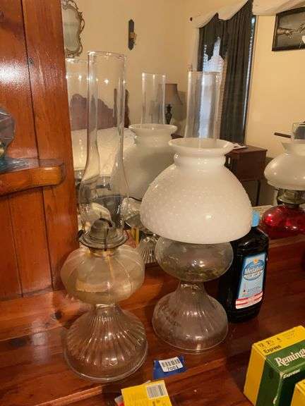 Two glass stand oil lamps, one has milk glass hobnail shade, and bottle of lamp oil