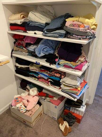 Contents of three shelves and on floor below: ladies clothing, tops, jeans, sweaters, shoes