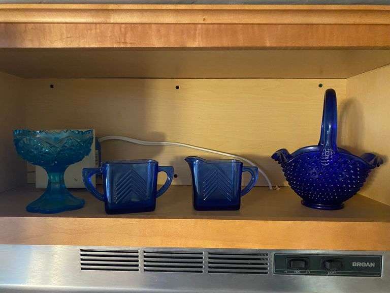 Contents of cupboard: cobalt blue depression glass sugar/creamer, cobalt hobnail basket, blue pedestal dish