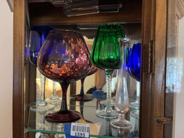 Contents of shelf: colored blown glass stemmed glasses, and swung glass bud vase