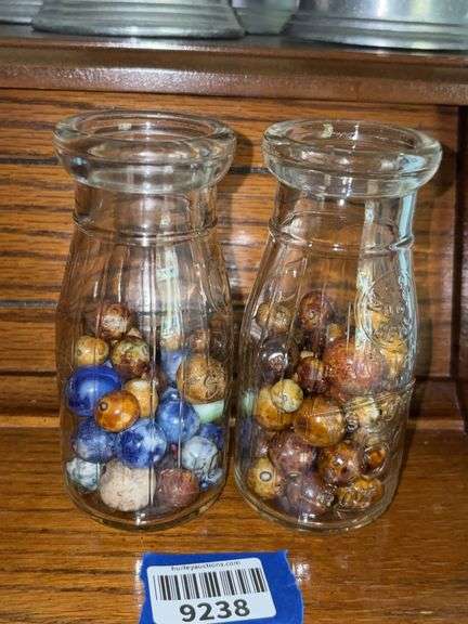 Two milk bottles of clay marbles