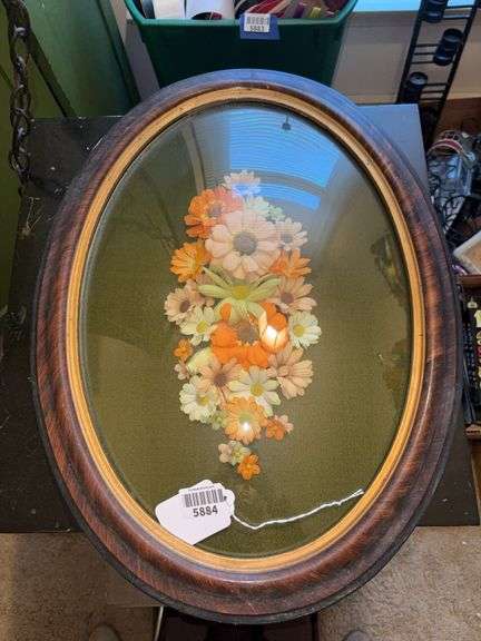 Oval frame w/ convex glass containing faux flowers17x24