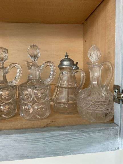 Four pressed pattern glass cruets and one syrup pitcher