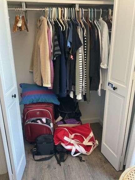 Contents of closet: men's and women's clothing, various sizes, luggage, pillow