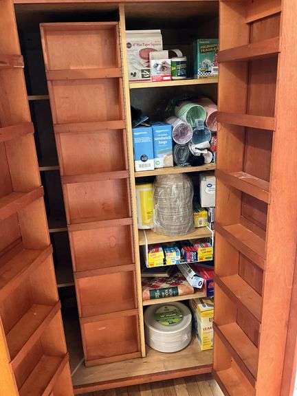 Contents of pantry cupboard: trash bags, paper goods, kitchen wrap, cookbook, misc