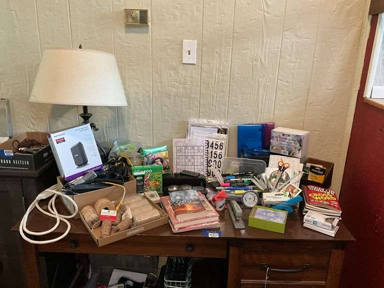 Contents of desk top and underneath: metal lamp, cable modem, twin, puzzles, office supplies, tape, waste cans, CDs, misc