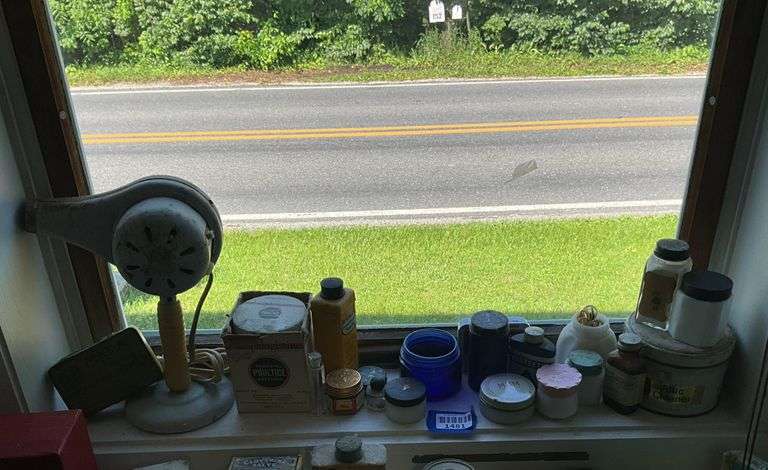 Early electric hair dryer and advertising tins and bottles on rear shelf of windowsill