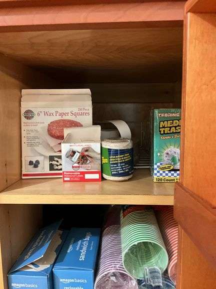 Contents of pantry cupboard: trash bags, paper goods, kitchen wrap, cookbook, misc