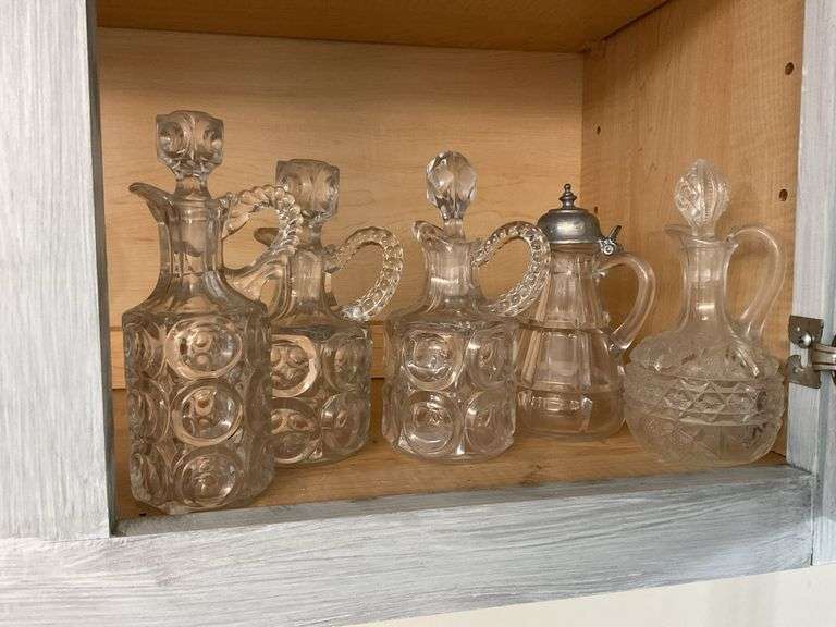 Four pressed pattern glass cruets and one syrup pitcher