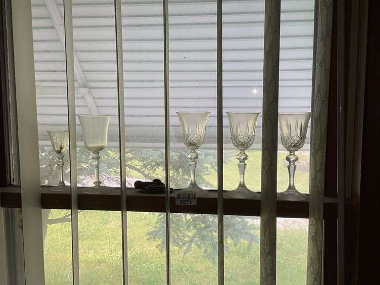 Glassware on two window ledges: crystal stemware, votive cups, cobalt bottles, vase