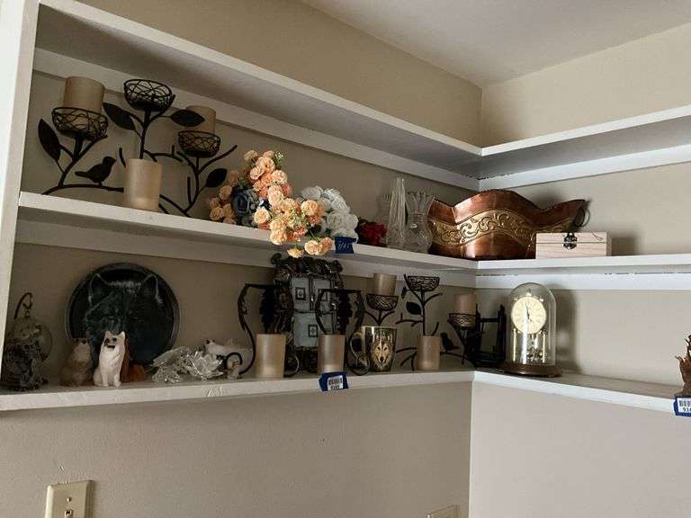 Contents of two shelves: anniversary style clock, votive holders, figurines, decor items