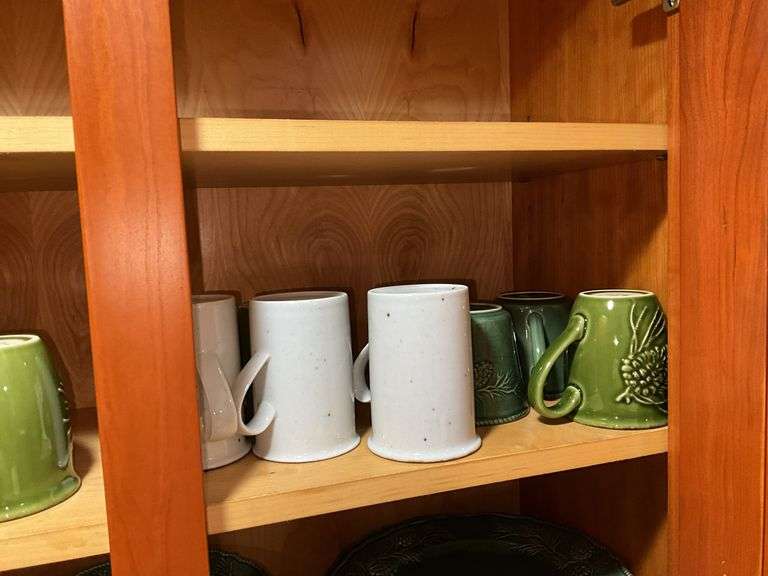 Contents of cupboard: Dansk stoneware dinnerware, green glazed pinecone motif dinnerware