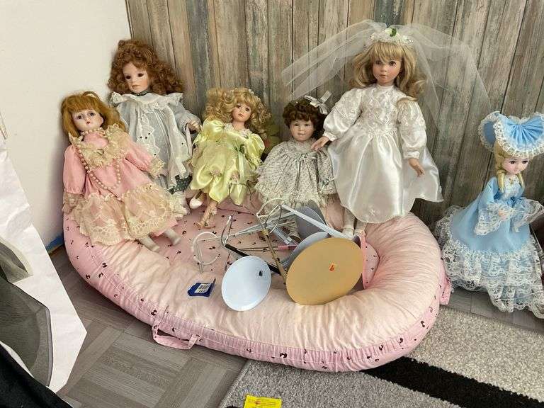 Five porcelain collector dolls, doll stands, cushion