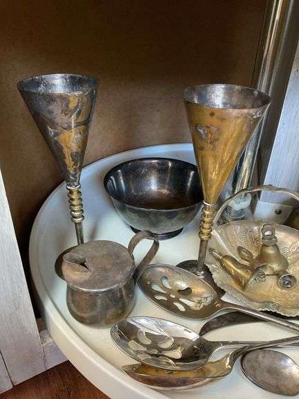 Contents of shelf: metalware - brass figurines and bells, aluminum basket, plated items, flatware