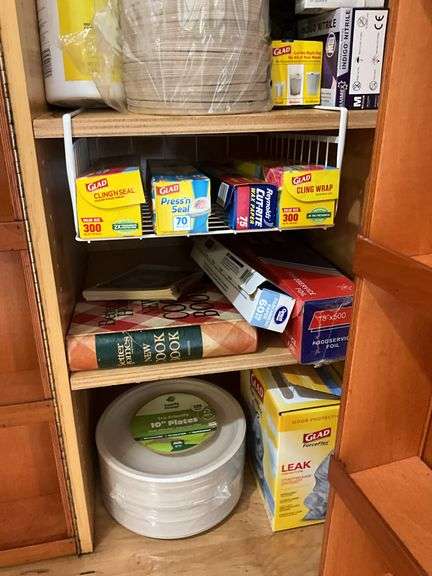 Contents of pantry cupboard: trash bags, paper goods, kitchen wrap, cookbook, misc
