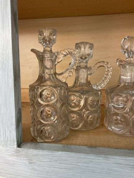 Four pressed pattern glass cruets and one syrup pitcher