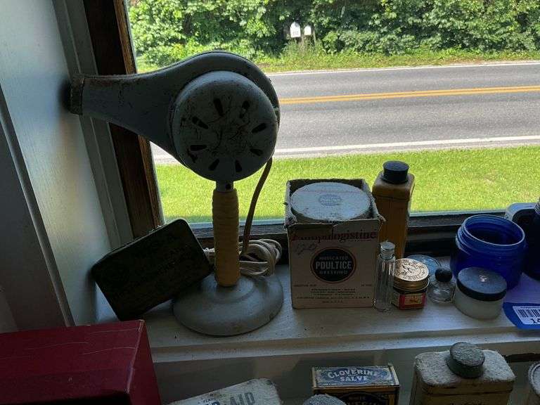 Early electric hair dryer and advertising tins and bottles on rear shelf of windowsill