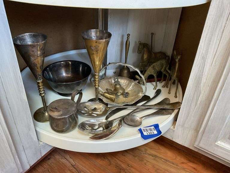 Contents of shelf: metalware - brass figurines and bells, aluminum basket, plated items, flatware