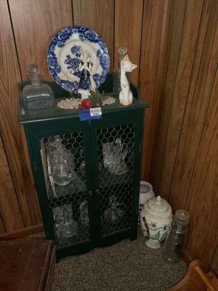 Country cupboard w/ chicken wire door panels and contents: cruets, flow blue plate, figurines, and vases on floor in corner