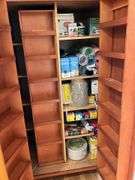 Contents of pantry cupboard: trash bags, paper goods, kitchen wrap, cookbook, misc