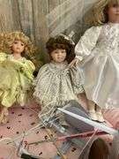 Five porcelain collector dolls, doll stands, cushion