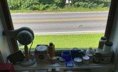 Early electric hair dryer and advertising tins and bottles on rear shelf of windowsill