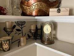 Contents of two shelves: anniversary style clock, votive holders, figurines, decor items