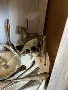 Contents of shelf: metalware - brass figurines and bells, aluminum basket, plated items, flatware