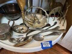 Contents of shelf: metalware - brass figurines and bells, aluminum basket, plated items, flatware