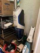 Contents of closet: MooSoo vacuum, Hoover upright vacuum, hand vac, cleaning supplies, Swiffer and refills, drawer unit, metal shelf unit, hangers, misc