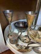 Contents of shelf: metalware - brass figurines and bells, aluminum basket, plated items, flatware